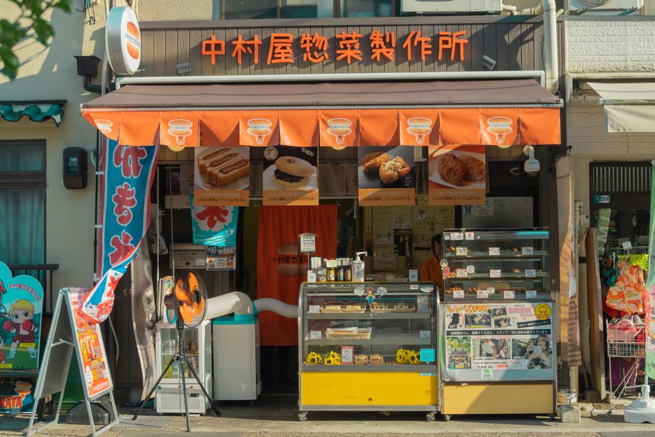 京都街邊熟食店掛著招牌與餐點看板，飄著在地生活氣息