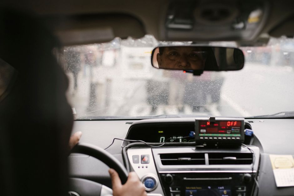 計程車儀表板亮著計費顯示器，司機專注看著後照鏡